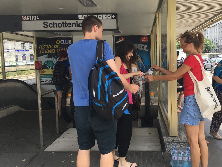 Bei der U-Bahn-Station Schottentor verteilen Mitarbeiterinnen und Mitarbeiter der Wiener Linien gratis kaltes Trinkwasser an Passagierinnen und Passagiere, denen sehr heiß ist.