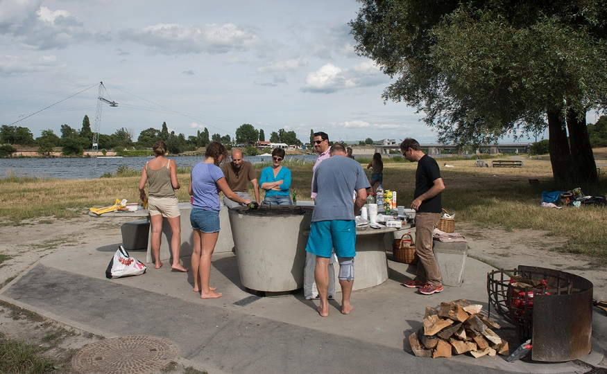 Gruppe von Menschen steht um einen Grillplatz auf der Donauinsel.