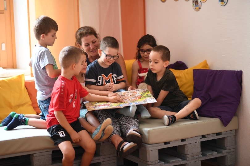 Kinder des Kindergartens Mengergasse in Floridsdorf sitzen mit ihrer Pädagogin auf den selbst gebauten Möbeln.