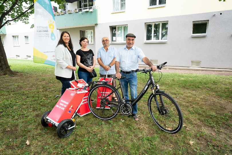 Wohnbaustadträtin Kathrin Gaal übergab „smarte“ Trolleys zum Einkaufen an Mieterin Loredana Grabner, Mieter Haci Yildiz und Mieter Abuzer Güzel (von links)