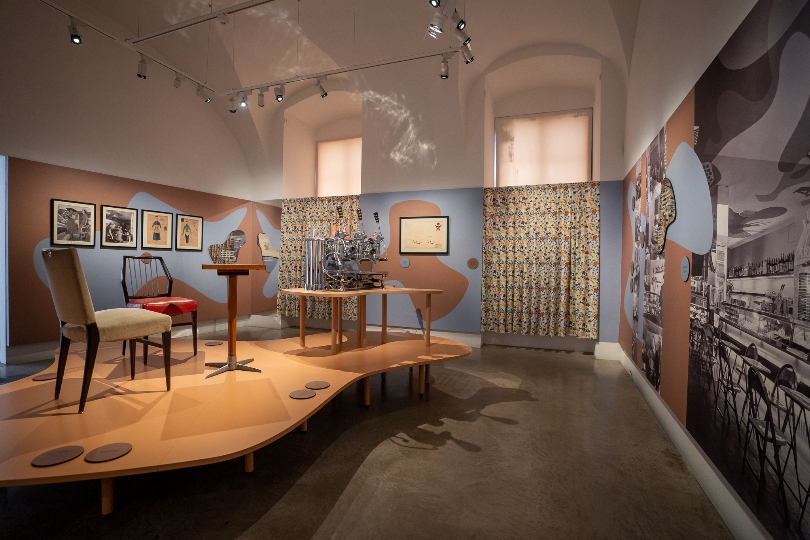 Ein Ausstellungsraum zeigt eine Cafehausszene mit zwei Sesseln und einem Tisch.