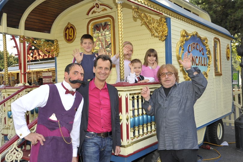 StR Christian Oxonitsch und Zirkusdirektor Bernhard Paul mit Kindern vor einem Zirkuswagen