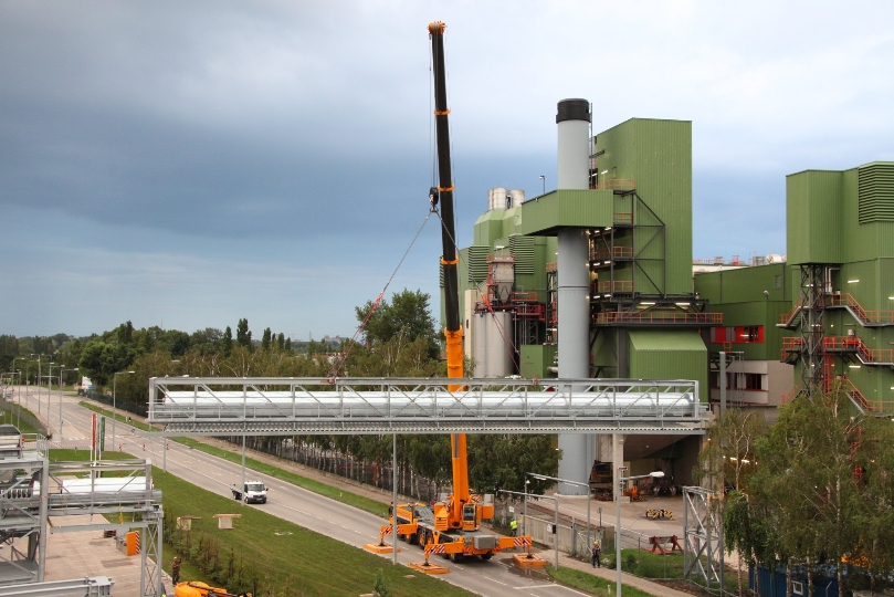 Die Förderbandbrücke wurde installiert. Es wiegt 25 Tonnen und befördert mit einer Geschwindigkeit von 3,6 km/h pro Stunde 94 Tonnen aufbereiteten Restmüll vom Abfalllogistikzentrum in einer Höhe von ca. 10 m über die Johann-Petrak-Gasse zum Werk der Fernwärme