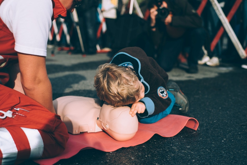Kind prüft Atmung bei einer Übungspuppe